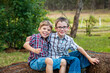 © Austockphoto - Two brothers sitting together on hay bales grinning