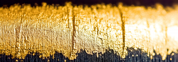 Aufkleber - Textured gold paint stroke on dark surface with artistic detail and abstract bokeh effect in horizontal composition