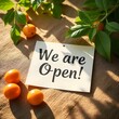 © Suntrimo - Minimalist flat lay of a small sign card with the words 'We Are Open' on a clean wooden table, natural sunlight, soft shadows, copyspace on background, high-resolution for product mockup