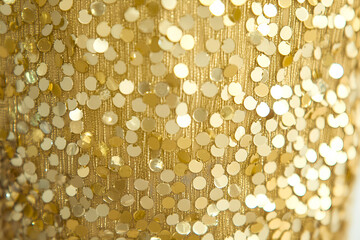 Poster - Close-up view of sparkling golden sequins embellishing a shimmering textile surface ideal for backgrounds or fashion designs.