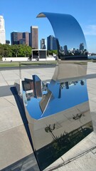 Poster - Modern sculpture with city skyline reflections in public space