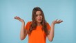 © kinomaster - Young woman expressing confusion in bright orange shirt