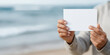 © Kate - A person holding a white card on a beach
