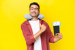 © luismolinero - Young handsome man with Inflatable Travel Pillow over isolated yellow background proud and self-satisfied