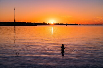 Wall Mural - silhouette of a man fishing at sunset at lake tawakoni state park, texas