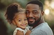 © Focus Gem - Portrait of happy black father and little daughter embracing, cute child girl cuddling daddy from the back and looking together aside at free space