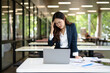 © maeching - Asian businesswoman working on financial market research using laptop and digital tablet, stressed about digital investment in office.