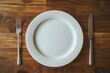 © kriengsak - Empty White Plate with Silverware on Rustic Wooden Tabletop