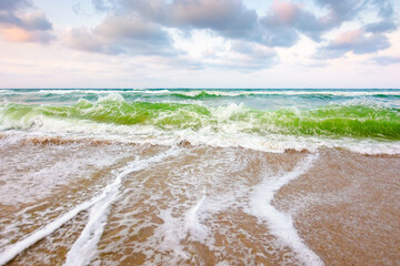 Wall Mural - nature background with sea tide in evening light. water surface motion at storm. wave splash with fo