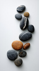 Poster - Smooth gray and brown stones arranged in a curve on white background, showcasing simplicity, balance, and natural serenity, ideal for spa or zen concepts