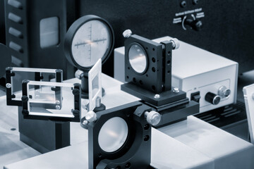 Leinwandbilder - Optical equipment including telescope and lenses are displayed on a table in a laboratory. Optics and photonics concept science experiment with laser background