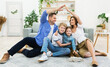© Prostock-studio - Family Housing And Relocation. Young Parents Joining Hands Making Symbolic House Roof Above Children Sitting At Home