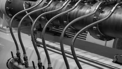 Poster - A series of pipes are connected to a large machine. The pipes are made of metal and are connected to each other. The machine is large and has a metallic appearance