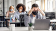 © Prostock-studio - New normal and brainstorming while working in office during covid-19 outbreak. Millennial man in protective mask rests his head on hands, sitting at table and looking at laptop at table with