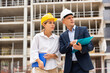 © JackF - Two young successful architects, controlling the progress of work on the construction site, discuss the construction plan, ..holding a laptop and a folder with drawings in their hands, making