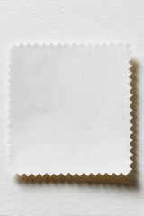 Poster - Close-up of White Fabric Swatch with Scalloped Edge on Textured Paper Background Studio Shot Overhead View