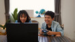© FAMILY STOCK - Asian teenage boy and girl playing video games at home together. Concept of digital lifestyle, esports, fun learning, teamwork, and modern entertainment for kids and teens indoors.