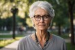© PRO STOCK'S - attractive grey-haired older woman in glasses standing outdoors alone in the summer park and staring at camera