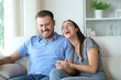 © Antonioguillem - Couple at home laughing hilariously on a couch