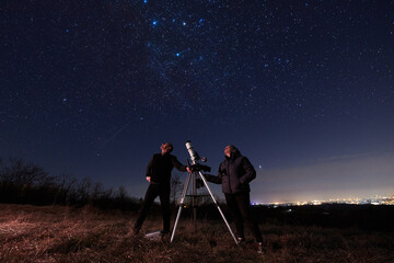Wall Mural - Amateur astronomers using telescope for watching stars, Moon, planets and other celestial objects from a field in nature.