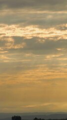 Sticker - Vertical Video Early Morning Timelapse with Layers of Clouds Moving Over Landscape. Light Rays Piercing Through Creating Ethereal Tone.