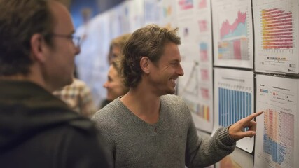 Poster - Startup company founder presenting positive growth metrics on colorful charts, explaining upward trends and key performance indicators to a coworker in a collaborative office environment