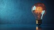 © bani - Glowing idea lightbulb on dark blue background, innovation concept, stock photo