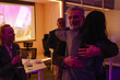 © Drobot Dean - A middle-aged Caucasian man hugs a young woman during an office celebration, surrounded by colleagues holding champagne glasses in a modern indoor workspace.