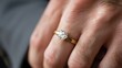 © ngalong project - Hand wearing a gold ring with a diamond against a blurred background.