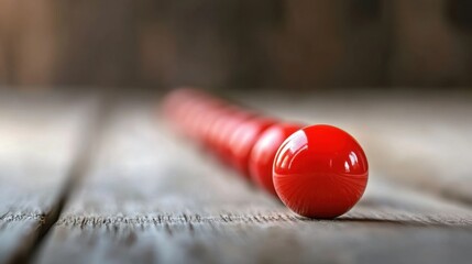 Poster - A vibrant red round object rests on a weathered wooden surface, creating a striking visual contrast. The blurred background enhances its focus and artistic appeal.