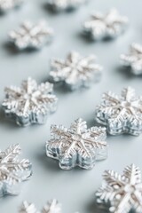 Poster - Macro close-up of silver snowflake decorations arranged on a light blue surface creating a festive winter holiday scene