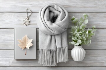 a fashion flatlay featuring a scarf, book, and maple leaf on a rustic wood background