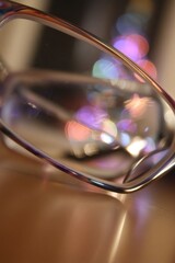 Poster - Eyeglasses Reflecting Bokeh Lights on Tabletop Close Up Abstract Still Life in Warm Tones for Vision Care or Festive Mood