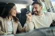 © Goran - Happy couple talking while sitting inside of their new car. Man is holding keys. The view is through glass.
