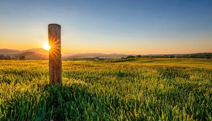 Aufkleber - sunlit rural field with wooden post and glowing sunset over rolling hills for nature-themed print, landscape web design, travel branding, or environmental presentation background

