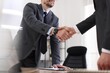 © New Africa - Men shaking hands at table in office, closeup