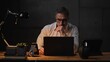 © nyul - Businessman sitting at desk with laptop computer. Entrepreneur working late in office. Older, middle aged, mid adult, man in his 40s or 50s in business casual.