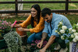 © La Famiglia - Happy couple gardening together, planting flowers in backyard