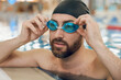 © zinkevych - Smiling bearded caucasian young man putting on swimming glasses