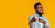 © Prostock-studio - It's your turn. Handsome black guy pointing fingers at camera and smiling over yellow background