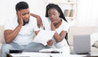 © Prostock-studio - Debt concept. Portrait of sad afro couple looking at invoice, upset about huge bills, not able to pay mortgage, sitting depressed on sofa at home