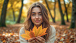© LarisaM - A woman is holding a leaf in her hand. She is smiling and looking at the camera. The image has a warm and peaceful mood, as the woman is surrounded by autumn leaves and he is enjoying the moment