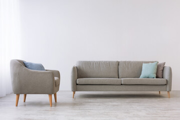 Poster - Cabinet or gray living room at home and minimalism in scandinavian design. Sofa with pillows and vintage armchair on wooden floor, on light wall background, mockup, flat lay, copy space, nobody