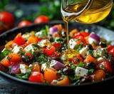 Close-up of fresh Mediterranean salad with tomatoes, olives, feta cheese, red onions, herbs, and olive oil being poured on top