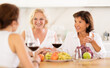 © JackF - Girlfriends chatting and drinking wine at home party table in kitchen