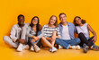 © Prostock-studio - Multiracial joyful students sitting on floor, embracing and having fun over yellow studio background, students lifestyle concept, panorama