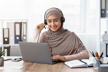 Aufkleber - Foreign Languages Online Concept. Portrait Of Smiling Arabic Girl In Hijab And Headset Watching Webinar On Laptop While Sitting In Office