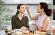 © JackF - Two female friends enjoying beauty routine in cozy home setting. Focused woman using makeup sponge to carefully apply foundation to perfect bestie look, evening out complexion