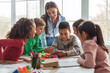© Prostock-studio - Multiethnic School Kids And Teacher Using Smartphone And Educational Application Learning Sitting At Desk In Modern Classroom At School. Education And Gadgets Concept. Selective Focus