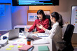 © Wasana - Two women are sitting at a desk with a laptop and papers